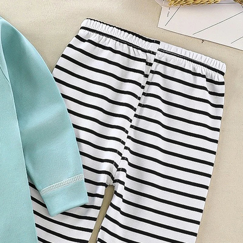 Black and white striped pants with a light blue shirt on a beige surface