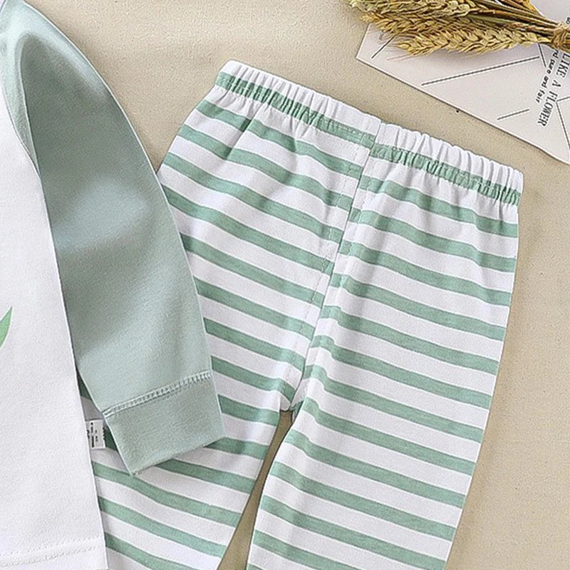 Green and white striped pants on a beige surface with a white shirt and dried plants.